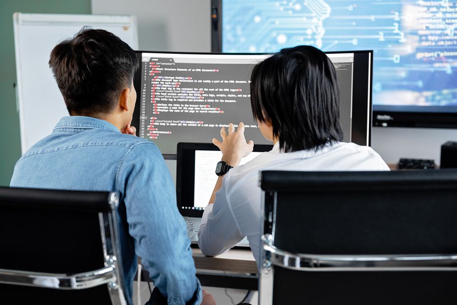 Dva programera zajedno rade na kodu na ekranu u uredu