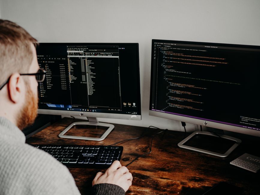 Programer radi na kodu s dva monitora u kućnom uredu